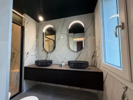 Bagno contemporaneo tra marmo e dettagli neri